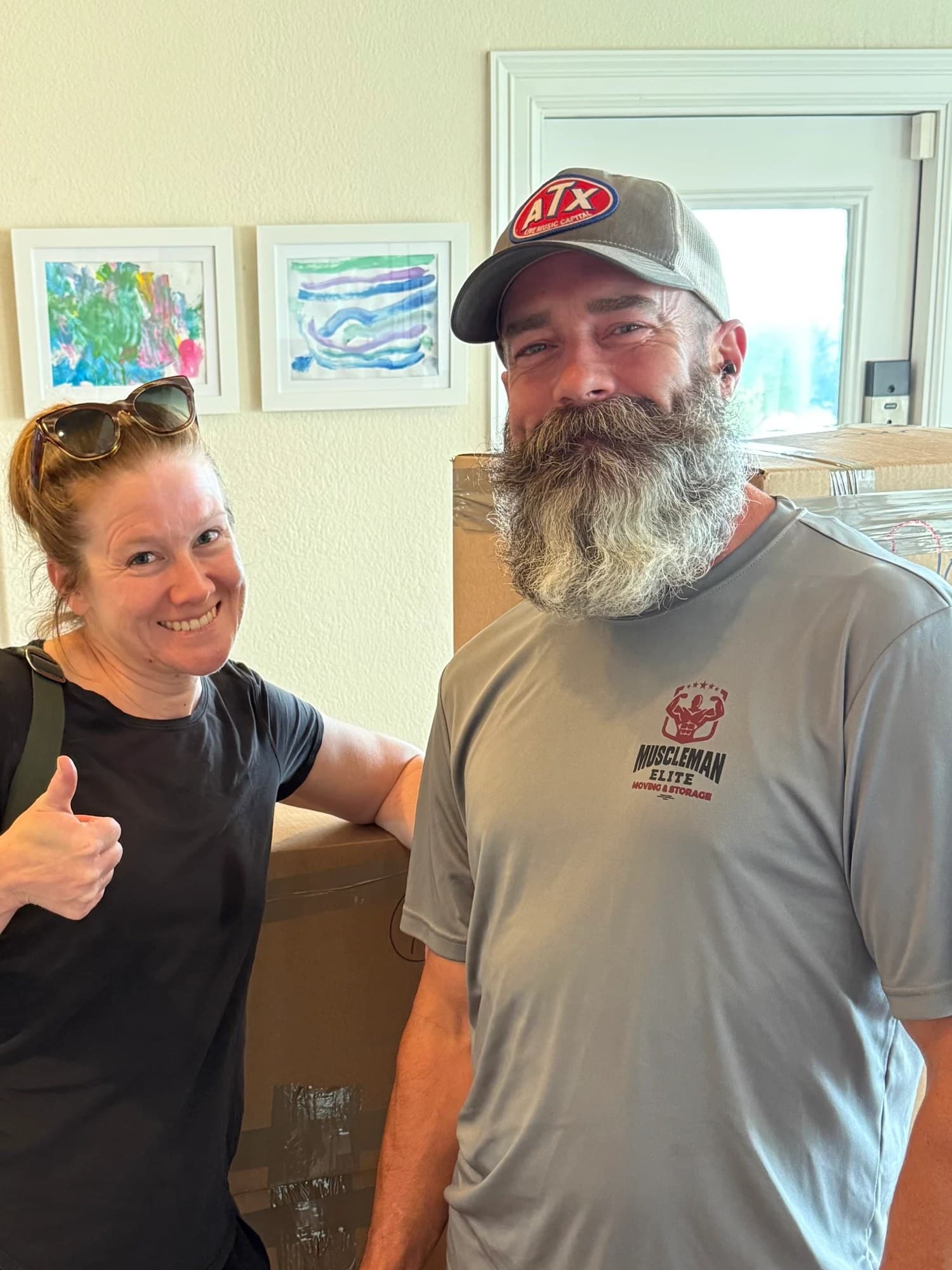 Muscleman Elite mover smiling with a customer beside packed boxes inside her home